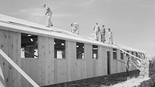 Historic image at Amache of contractor's workmen roofing an assembled barracks unit.