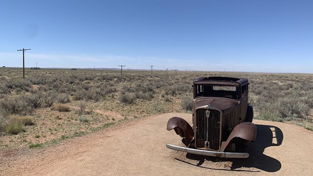 A historic, rusted car in the desert.