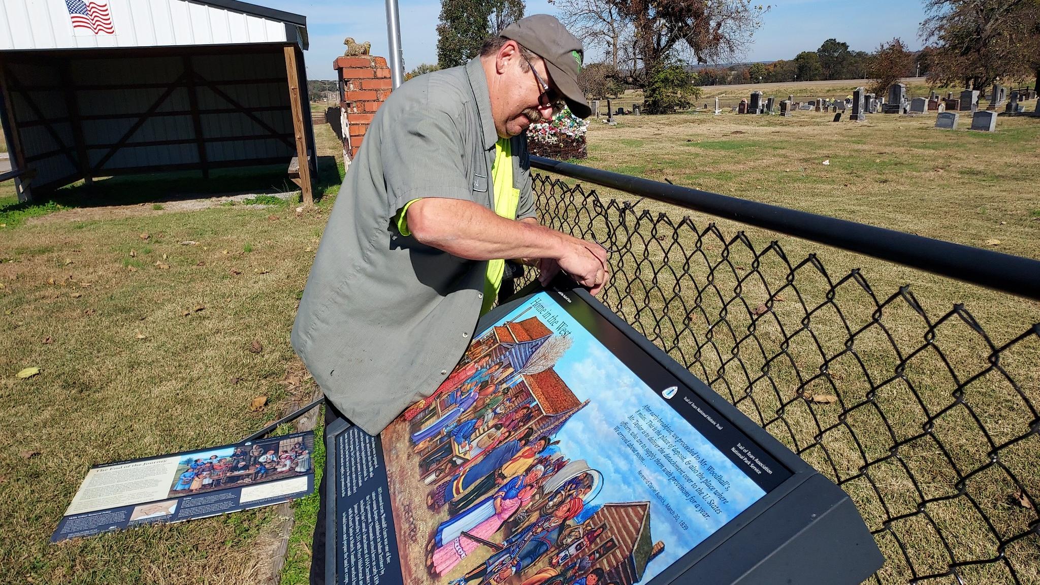Partner installing an exhibit next to a fence with a building behind.