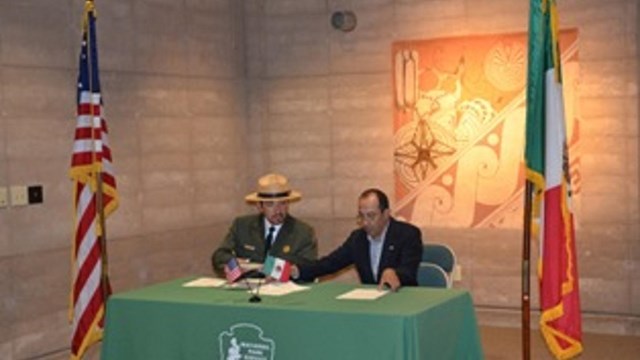 two men signing document at table