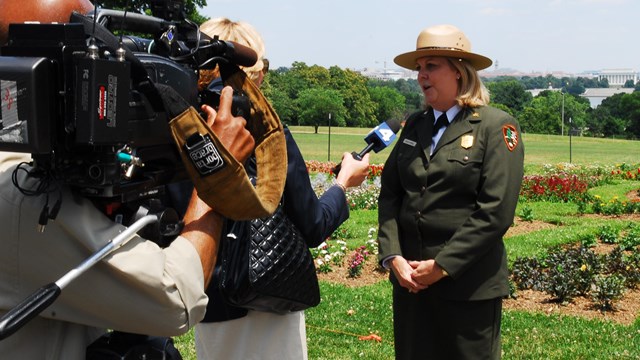 An NPS official speaks to a reporter and cameraman.