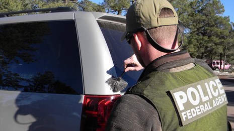 An ISB Special Agent dusts a vehicle for fingerprints. NPS photo.