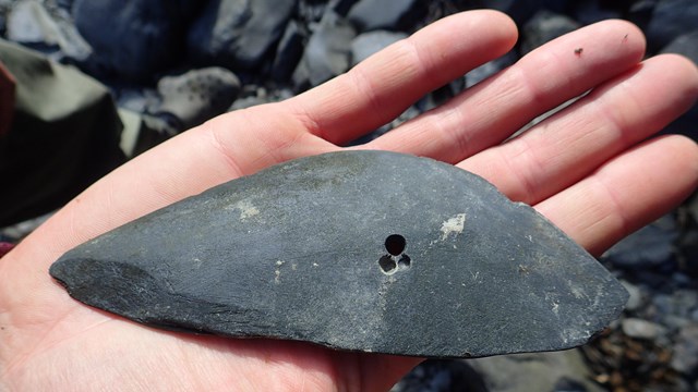 Hand holding a shaped stone tool 