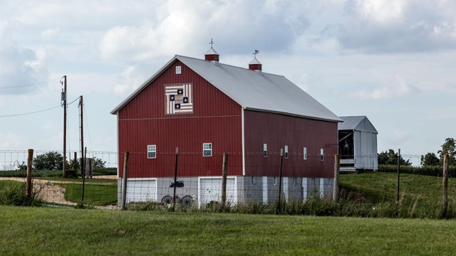Photograph of red frame barn exterior on a sunny day.