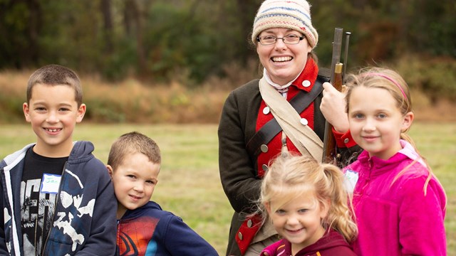 Children pose next to a Revolutionary War soldier.
