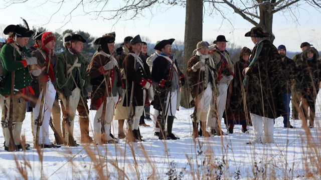 A line of people in Revolutionary War clothing