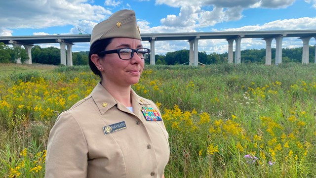 USPHS Officer stands in uniform with green grass and blue sky in background