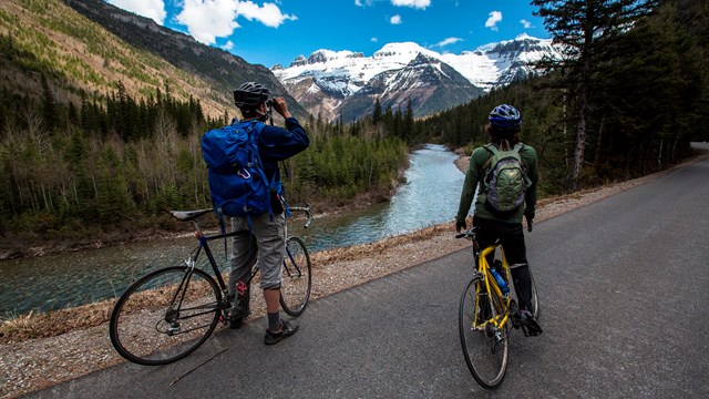 cyclists stop on a path to admire a glacier in the distance