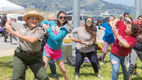 park ranger and visitors dance in a park