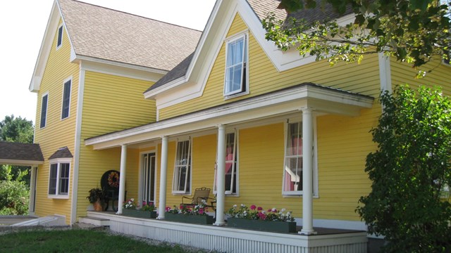 photo of a yellow house with storm windows