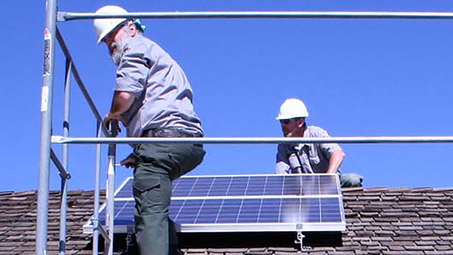 photo of workers installing solar panels on a roof