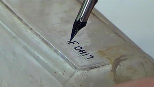 Close-up of a historic glass bottle with a label being applied with a fountain pen and archival ink