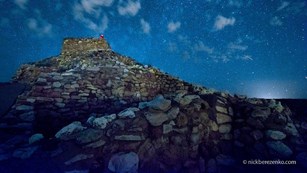 Stone walls with bluish starry sky and clouds above.