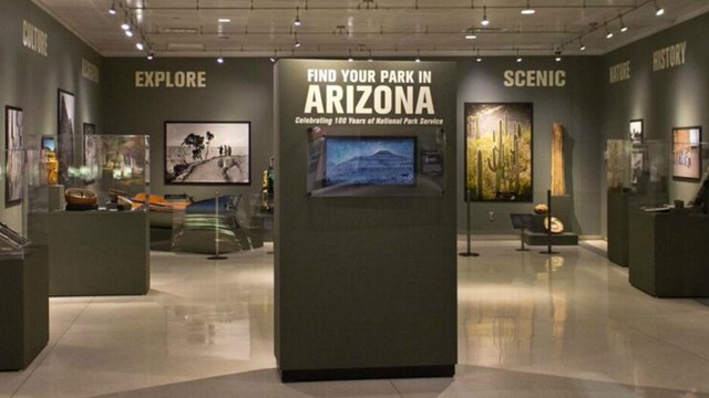 An interior view of a museum with grey walls and photos of national parks hanging.