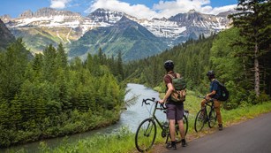 Two bikers overlooking a river at Glacier National Park.