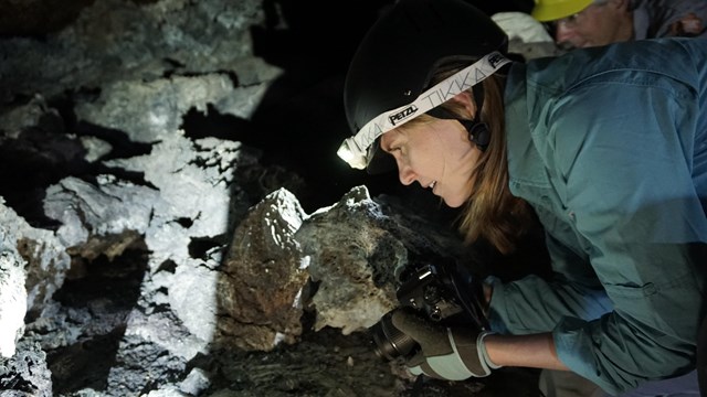 a woman examines a cave wall