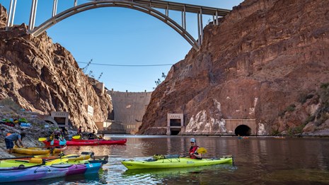 Kayak with pilot at waters edge, Hoover Dam and bridge in distance