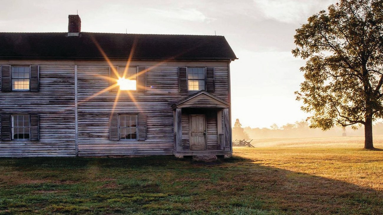 Rays from the setting sun stream through the window of the wood sided Henry House at Manassas Nation