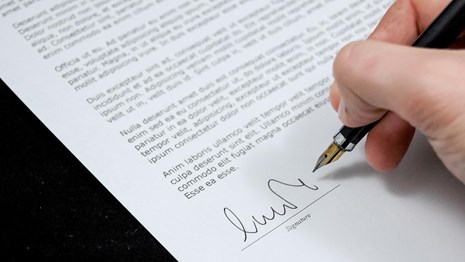 Hand with fancy pen signs document