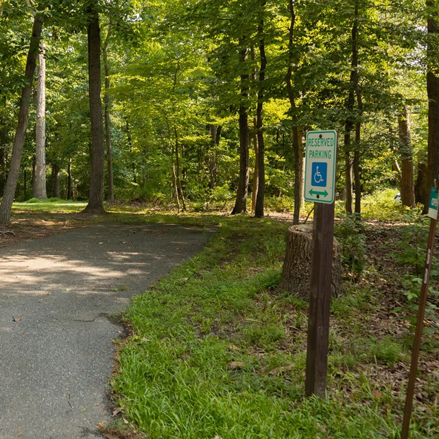 A handicapped parking sign near a paved trail.