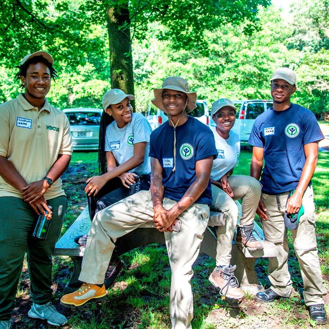 A group of young people in volunteer shirts pose for a photo.