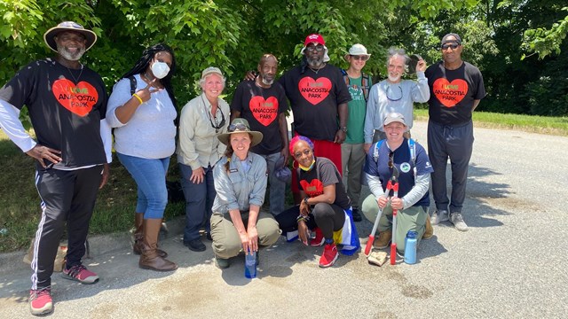 Volunteers standing together in a group by trees. 