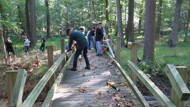 Volunteers fixing a wooden bridge. 