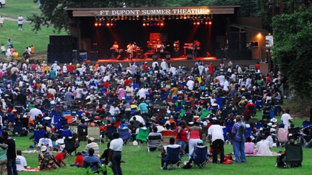 A crowd of people watching a concert on a stage. 