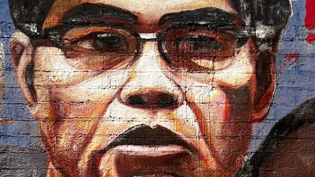 Mural painting of Philip Vera Cruz looks off to the side.