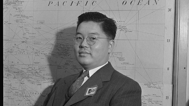Black and white photo of Jack Maki, regional specialist for Japan, looks at the camera in a suit.