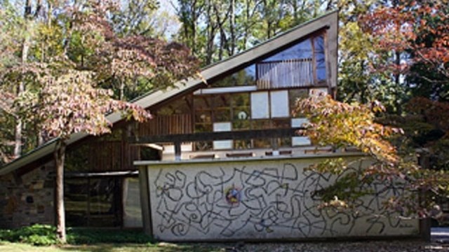 Color photograph of an angular building with a sloped roof and abstract squiggles painted on wall.