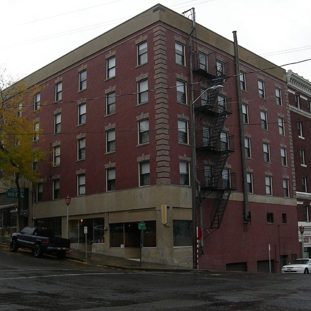 Multi-storied brick building with fire escape on side. By Joe Mabel, CC BY-SA 3.0. 
