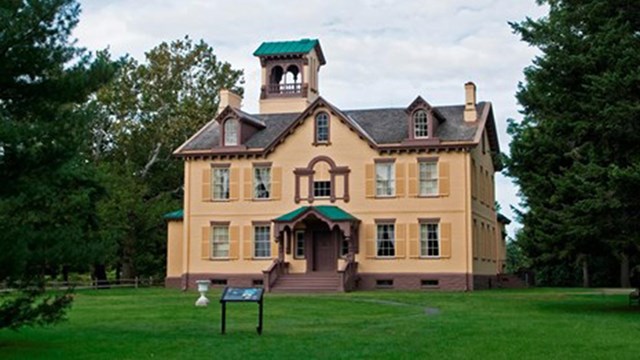 a gabled two story house with a clearstory on top surrounded by a lush green lawn