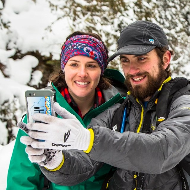 Two visitors taking a selfie in a snowy, wooded area