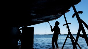 Deck hand Joe Mandusa works to clean the underside of the 151′ Schooner Margaret Todd in Hulls Cove