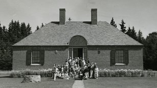 Historic photograph of a brick building with people grouped in front