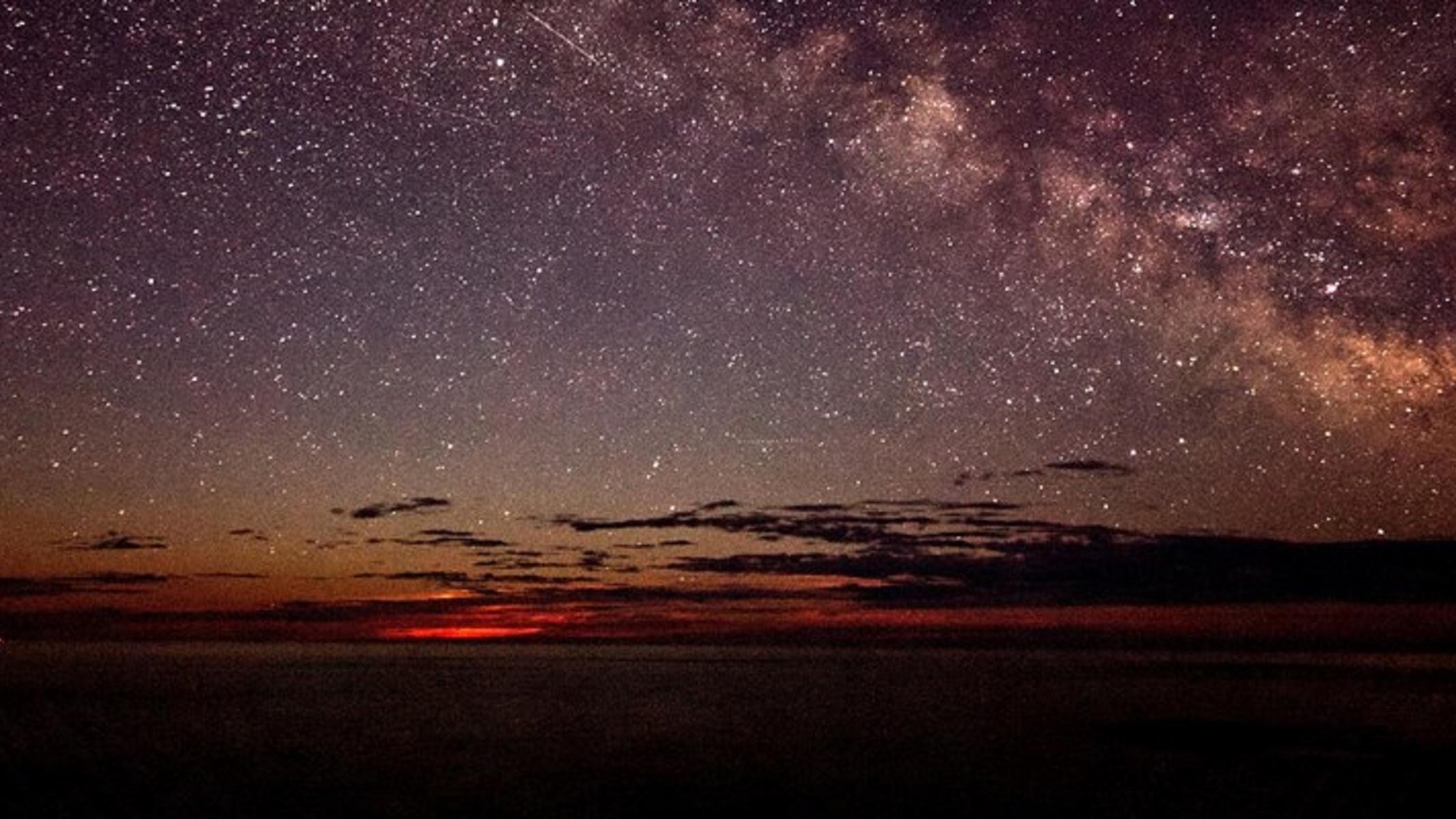 Many stars shine over a glowing horizon