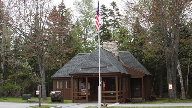 A wooden ranger station with a flag pole and driveways leading up to it