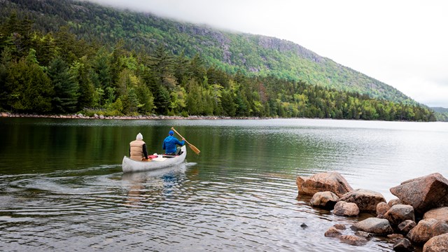 Two people rowing a canoe on a pond