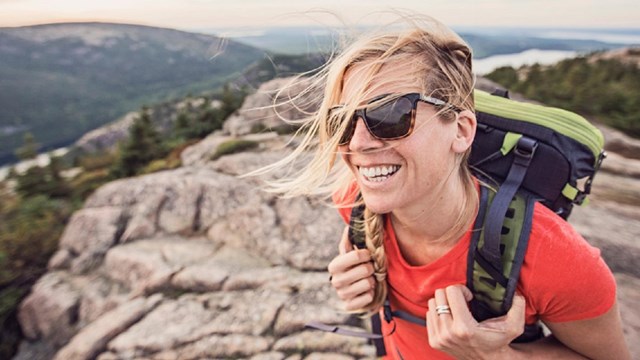 Woman hikes across bridge over creek