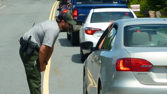 A park ranger speaks with visitors through a car window