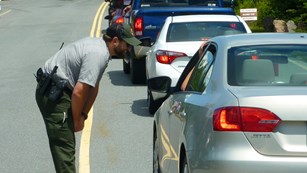 A park ranger speaks with visitors through a car window