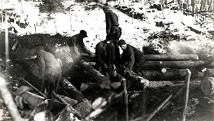 Workers building a wooden bridge in a forested area