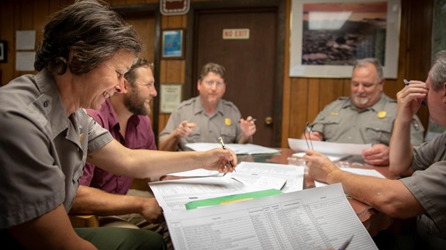 Person in a meeting room with others looking at paperwork