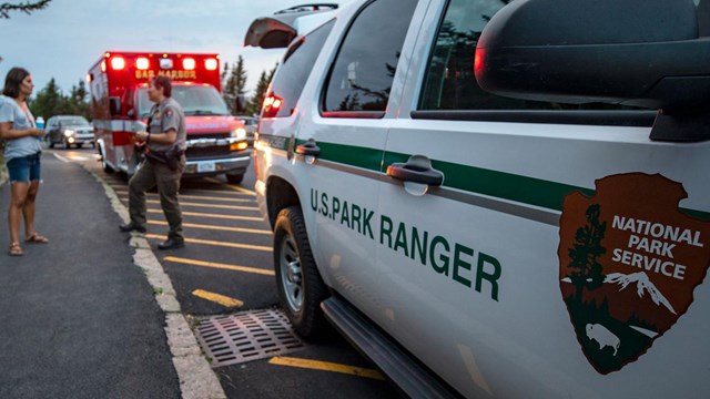 a ranger talks to a visitor in front of emergency vehicles