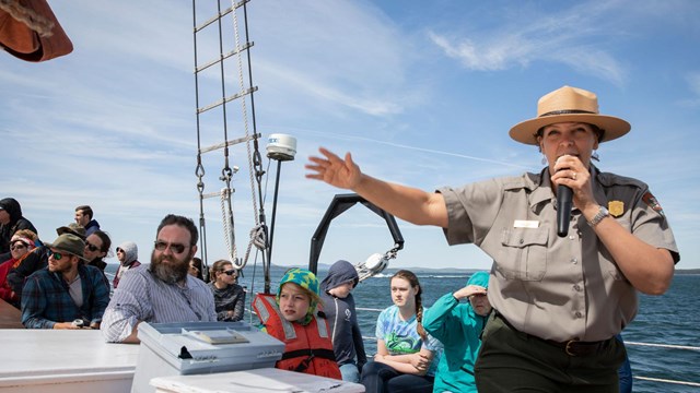 a ranger speaks with the public on a boat