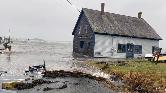 Flooding and damage to buildings along a coastline during a winter storm.