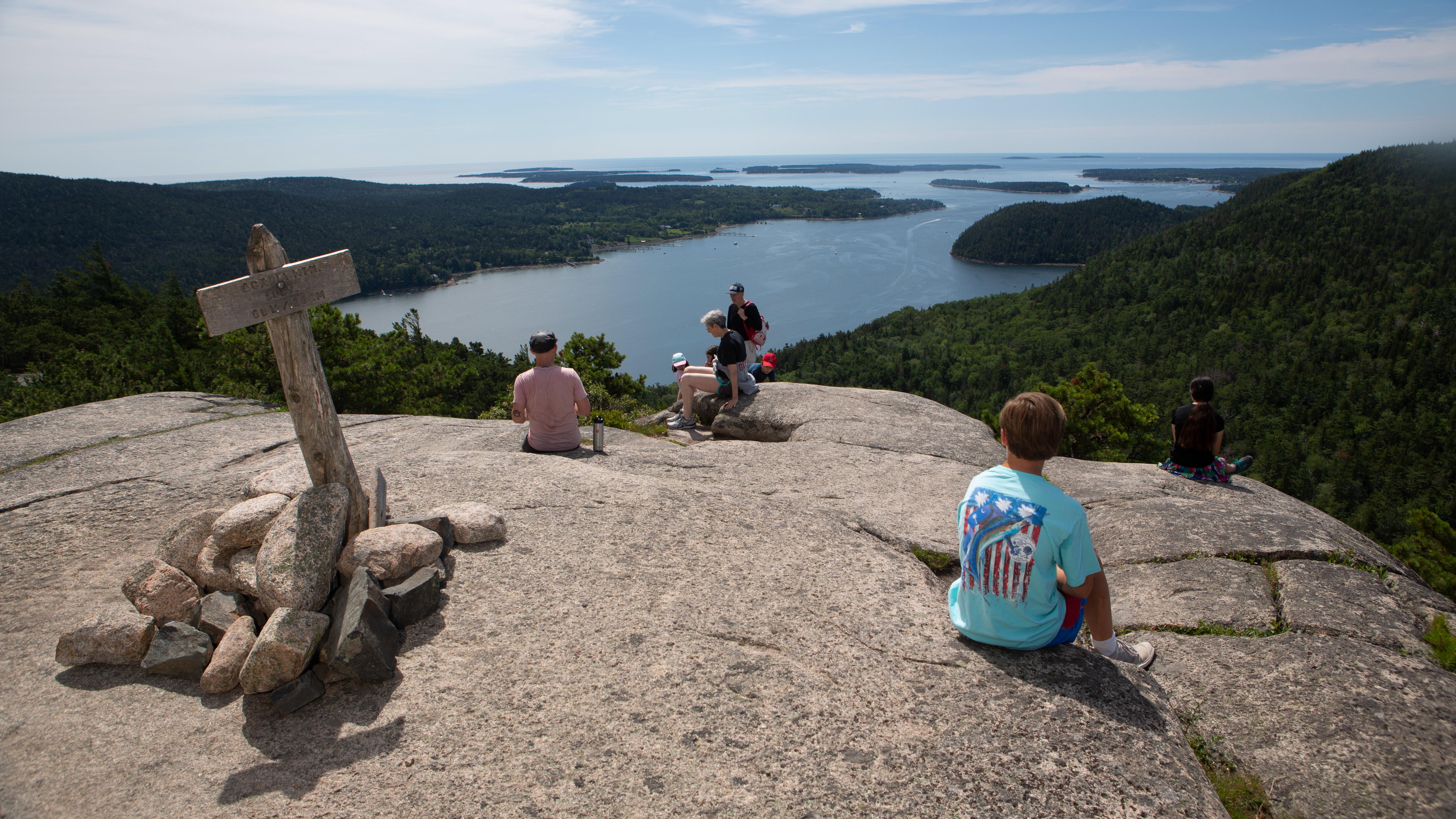 Hikers on mountain summit overlooking water, Acadia