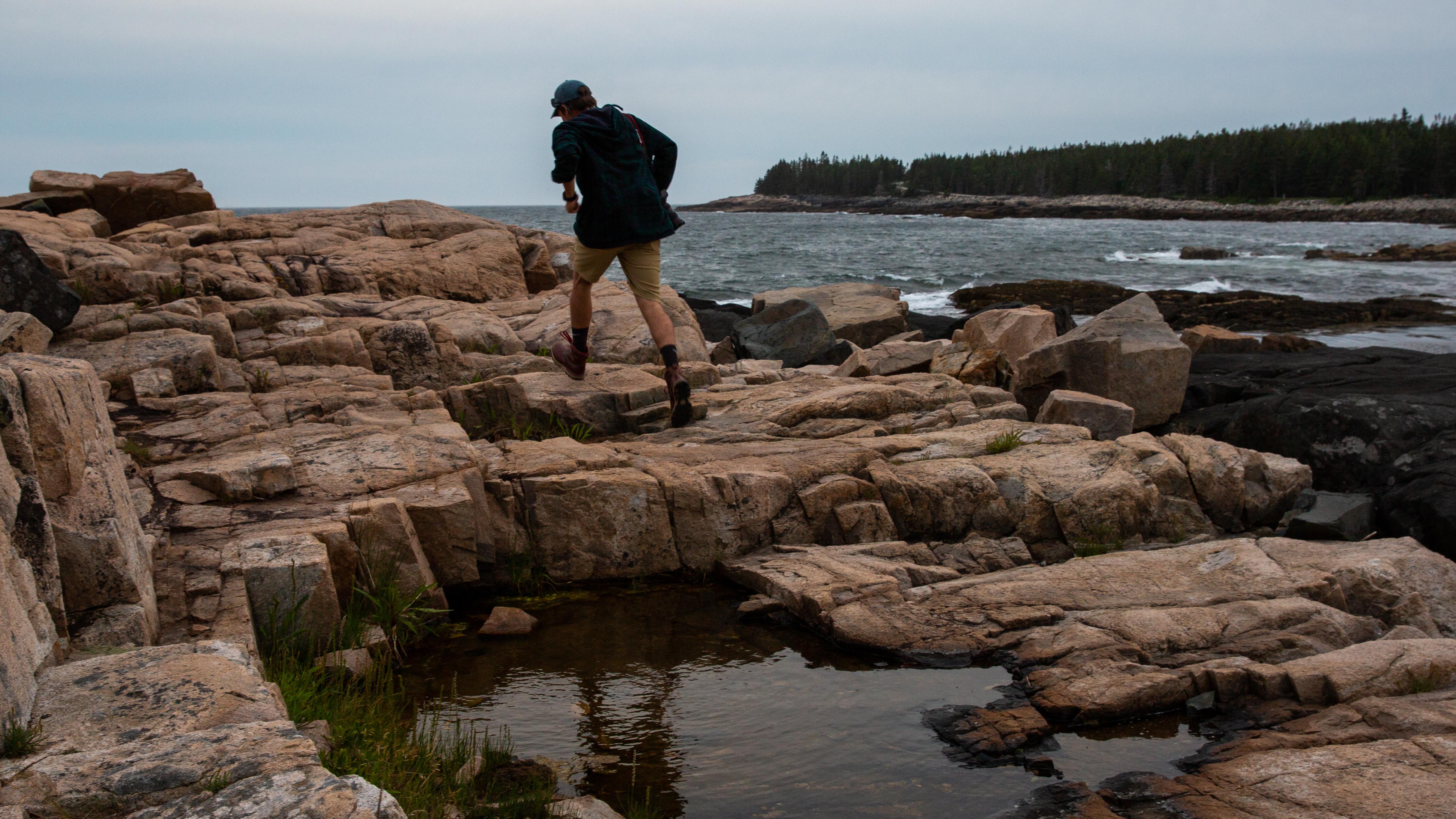 Person walking along rocky coastline, Acadia National Park