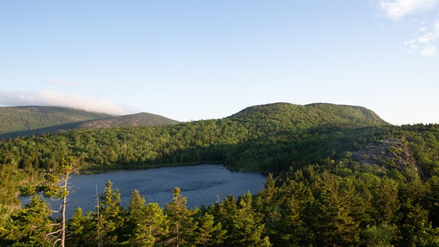 Two mountains and a body of water surrounded by a forest